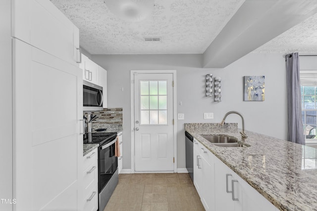 8361 Mcguire Dr, Raleigh, NC 27616 - kitchen with stainless steel appliances, a textured ceiling, light stone counters, white cabinetry, and tasteful backsplash