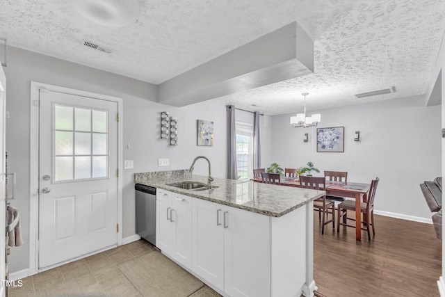 8361 Mcguire Dr, Raleigh, NC 27616 - kitchen with stainless steel dishwasher, a textured ceiling, a peninsula, white cabinets, and a chandelier