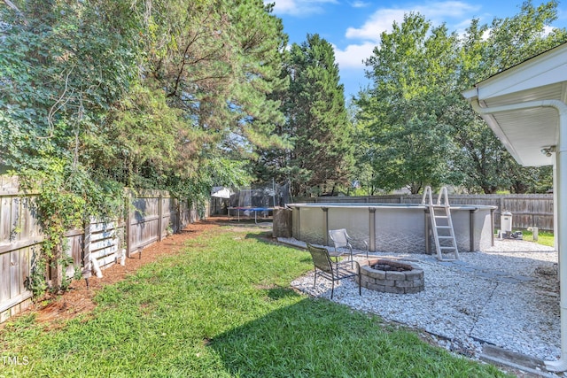 8361 Mcguire Dr, Raleigh, NC 27616 - fenced backyard featuring a trampoline, a fire pit, and a patio area