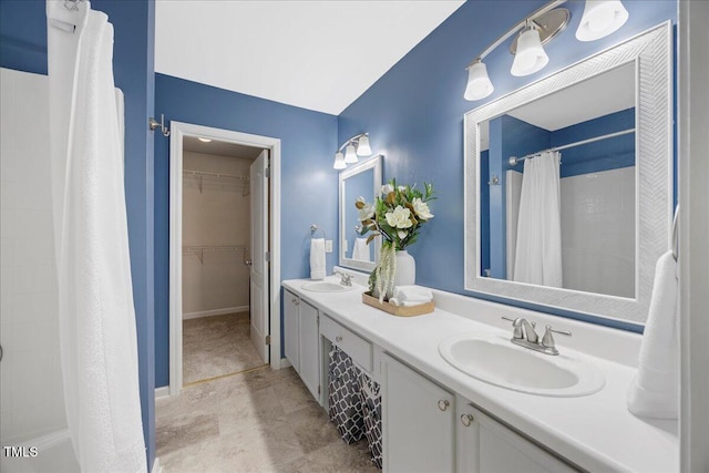 4805 Castle Crest Ct, Raleigh, NC 27616 - bathroom featuring a tile shower, double vanity, a walk in closet, and baseboards