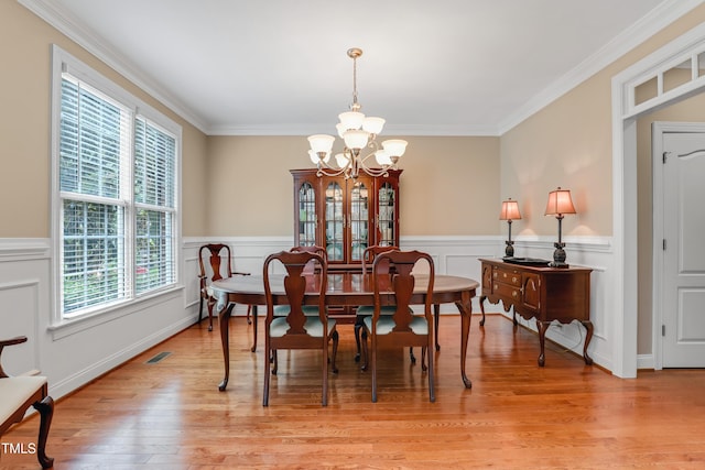 225 Norwalk St, Holly Springs, NC 27540 - dining space featuring a chandelier, crown molding, light wood finished floors, and a wainscoted wall