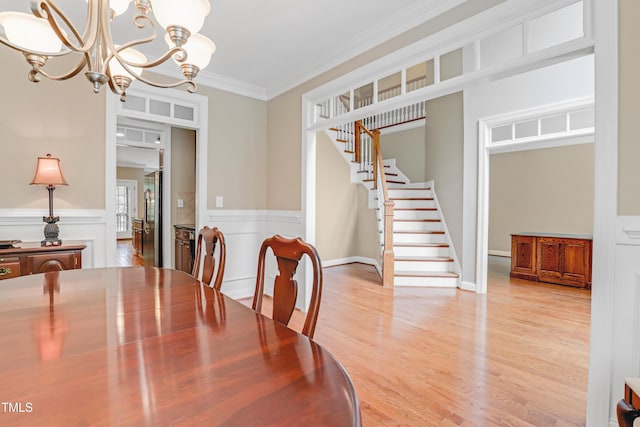225 Norwalk St, Holly Springs, NC 27540 - dining space featuring a chandelier, stairway, light wood finished floors, ornamental molding, and a wainscoted wall