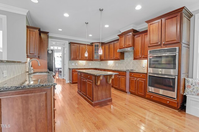 225 Norwalk St, Holly Springs, NC 27540 - kitchen with stainless steel double oven, a sink, brown cabinets, dark stone counters, and light wood finished floors