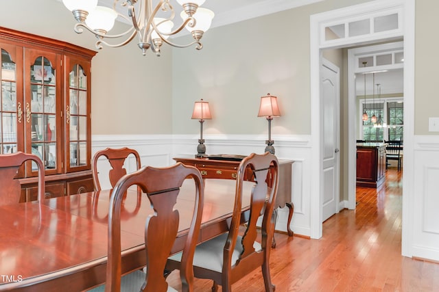 225 Norwalk St, Holly Springs, NC 27540 - dining area featuring a chandelier, light wood finished floors, wainscoting, a decorative wall, and ornamental molding
