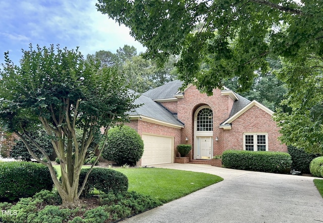 200 Greensview Dr, Cary, NC 27518 - view of front of home with brick siding, an attached garage, driveway, a shingled roof, and a front lawn