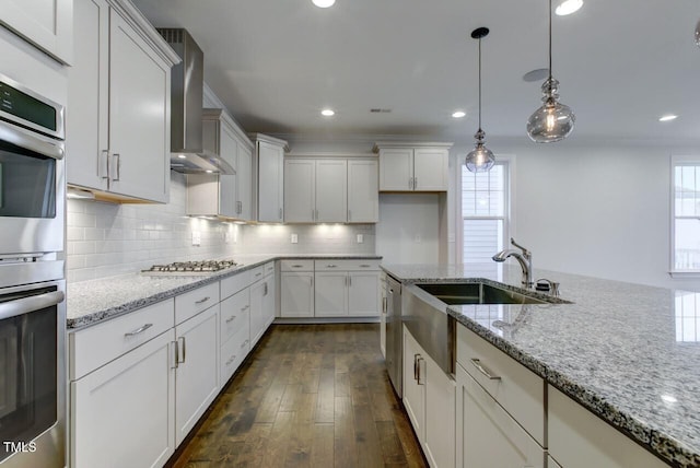 2309 Redbridge Ln, Apex, NC 27502 - kitchen with wall chimney range hood, healthy amount of natural light, appliances with stainless steel finishes, a sink, and recessed lighting