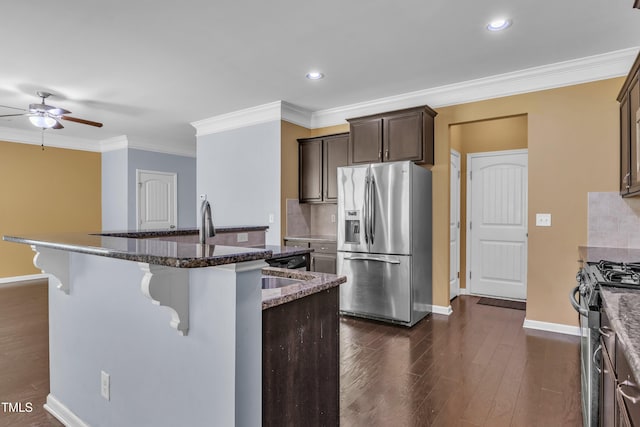 211 Westgrove Ct, Durham, NC 27703 - kitchen with appliances with stainless steel finishes, a ceiling fan, a kitchen breakfast bar, baseboards, and ornamental molding