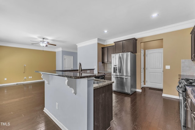 211 Westgrove Ct, Durham, NC 27703 - kitchen with stainless steel appliances, ceiling fan, baseboards, a breakfast bar, and a center island with sink