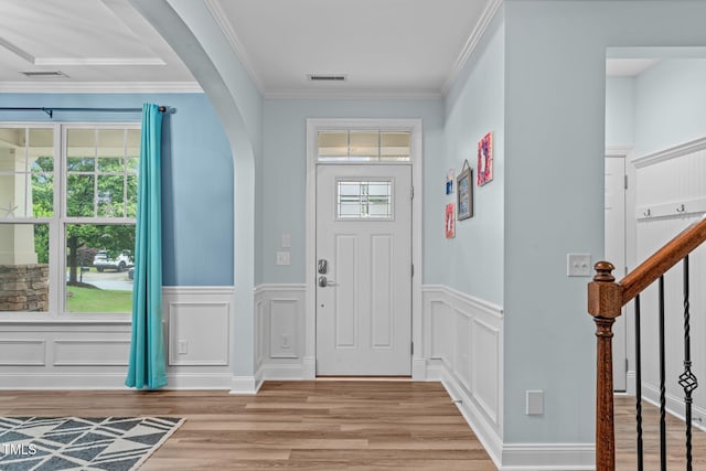 1939 Mostyn Ln, Apex, NC 27502 - entryway featuring arched walkways, light wood finished floors, wainscoting, crown molding, and a decorative wall
