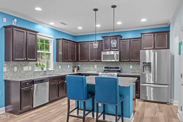 1939 Mostyn Ln, Apex, NC 27502 - kitchen featuring appliances with stainless steel finishes, dark brown cabinetry, a sink, light wood-style flooring, and crown molding