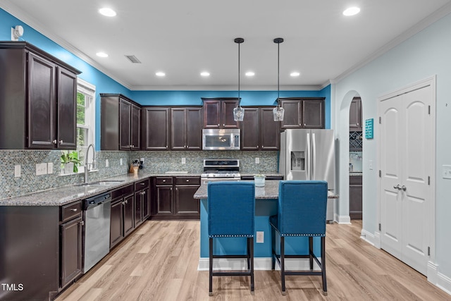 1939 Mostyn Ln, Apex, NC 27502 - kitchen with stainless steel appliances, a sink, dark brown cabinetry, arched walkways, and light wood-style floors
