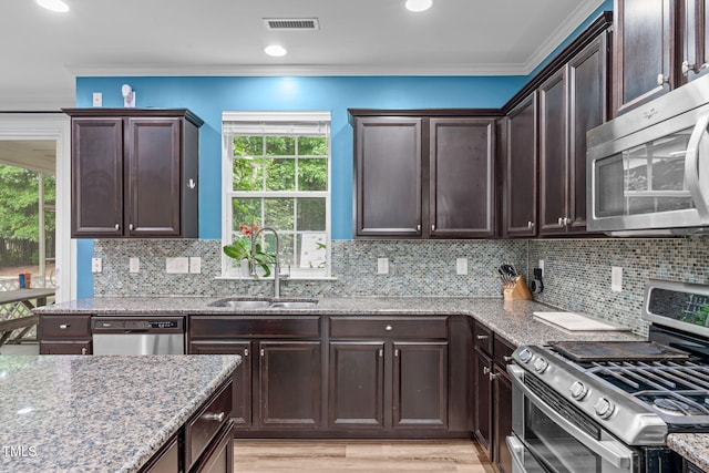 1939 Mostyn Ln, Apex, NC 27502 - kitchen featuring appliances with stainless steel finishes, a sink, light stone counters, dark brown cabinets, and plenty of natural light