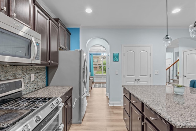 1939 Mostyn Ln, Apex, NC 27502 - kitchen featuring stainless steel appliances, arched walkways, crown molding, dark brown cabinets, and backsplash