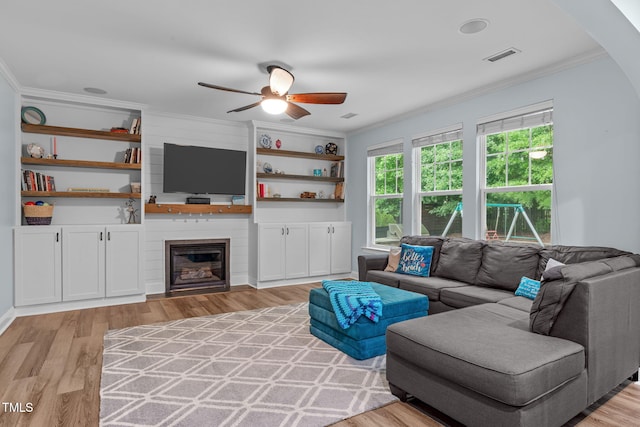 1939 Mostyn Ln, Apex, NC 27502 - living area with ornamental molding, a ceiling fan, light wood finished floors, a fireplace, and built in shelves