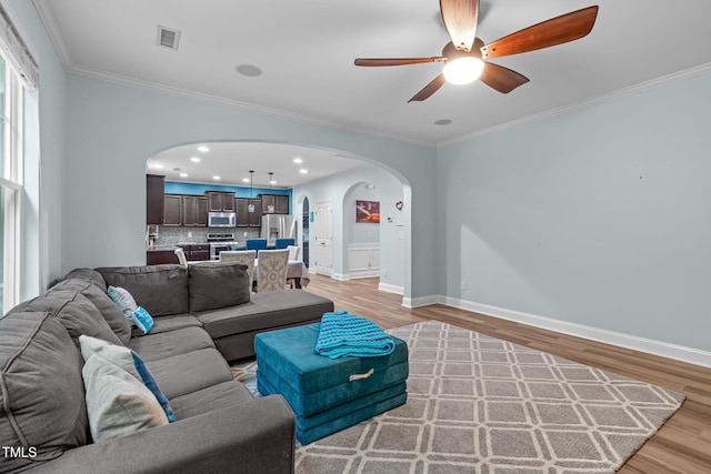 1939 Mostyn Ln, Apex, NC 27502 - living room featuring arched walkways, light wood-type flooring, ceiling fan, ornamental molding, and baseboards