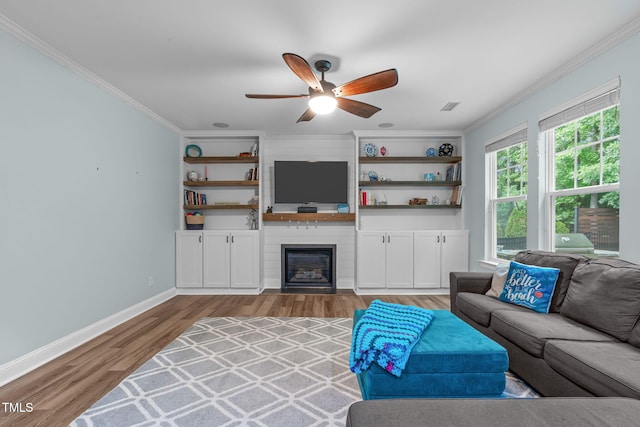 1939 Mostyn Ln, Apex, NC 27502 - living room featuring crown molding, ceiling fan, wood finished floors, baseboards, and a large fireplace
