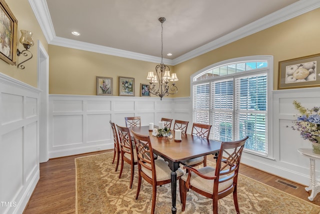 105 Somerley Dr, Garner, NC 27529 - dining area featuring a decorative wall, crown molding, a chandelier, wood finished floors, and a wainscoted wall