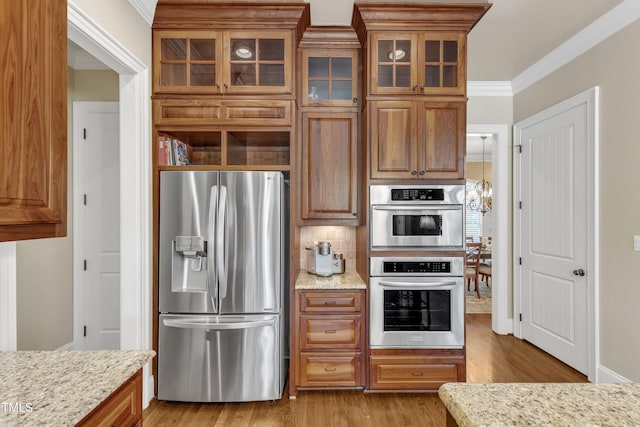 105 Somerley Dr, Garner, NC 27529 - kitchen with stainless steel appliances, wood finished floors, brown cabinetry, ornamental molding, and light stone counters