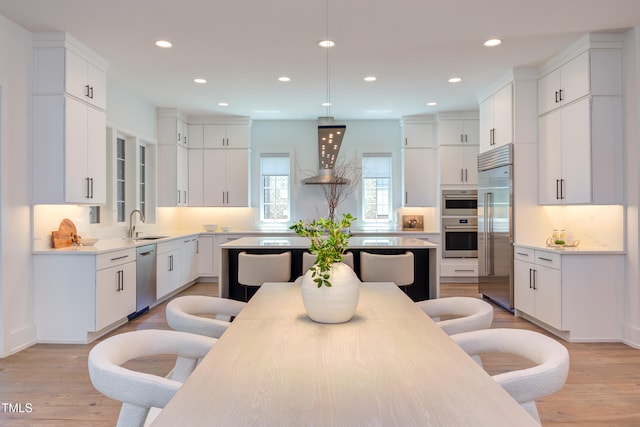 2114 Cowper Dr, Raleigh, NC 27608 - kitchen featuring stainless steel appliances, ventilation hood, light wood-style floors, white cabinets, and light countertops