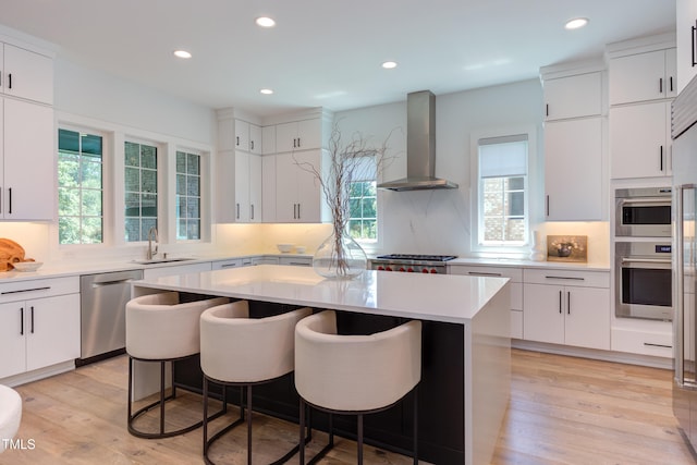 2114 Cowper Dr, Raleigh, NC 27608 - kitchen featuring wall chimney exhaust hood, dishwasher, light countertops, a kitchen breakfast bar, and a kitchen island