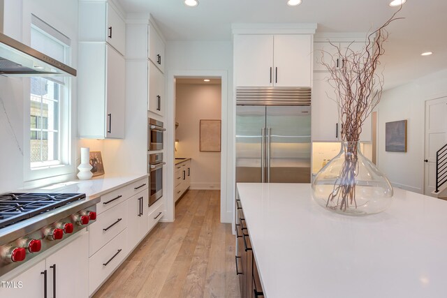 2114 Cowper Dr, Raleigh, NC 27608 - kitchen featuring wall chimney range hood, recessed lighting, stainless steel gas cooktop, white cabinets, and light wood-type flooring