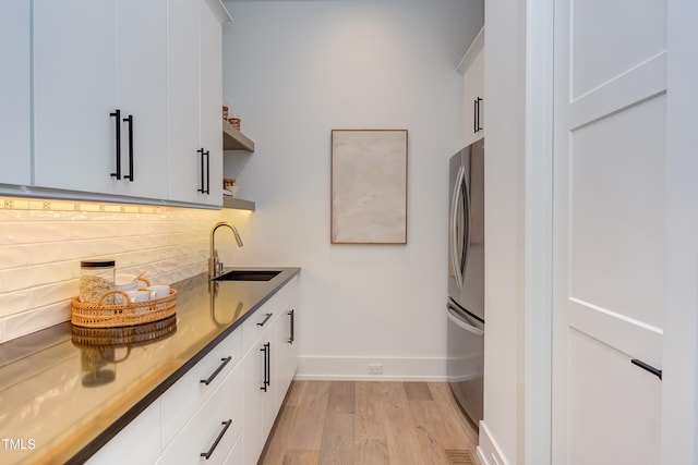 2114 Cowper Dr, Raleigh, NC 27608 - kitchen featuring light wood-style flooring, freestanding refrigerator, white cabinets, decorative backsplash, and open shelves