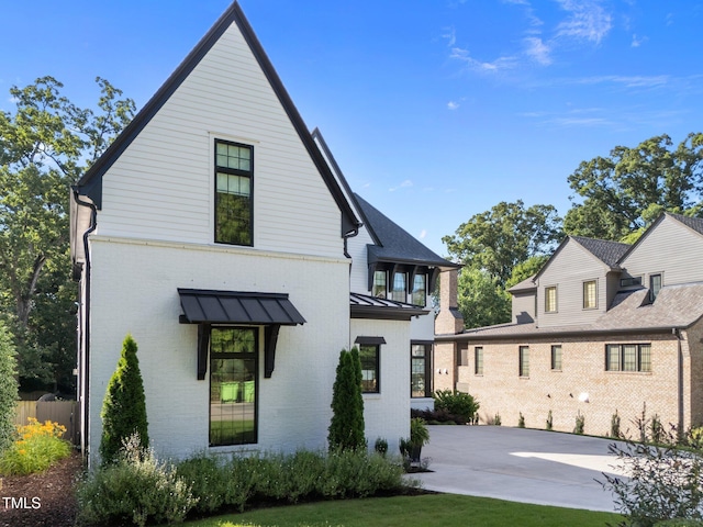 2114 Cowper Dr, Raleigh, NC 27608 - view of front of property featuring brick siding, a standing seam roof, and a metal roof
