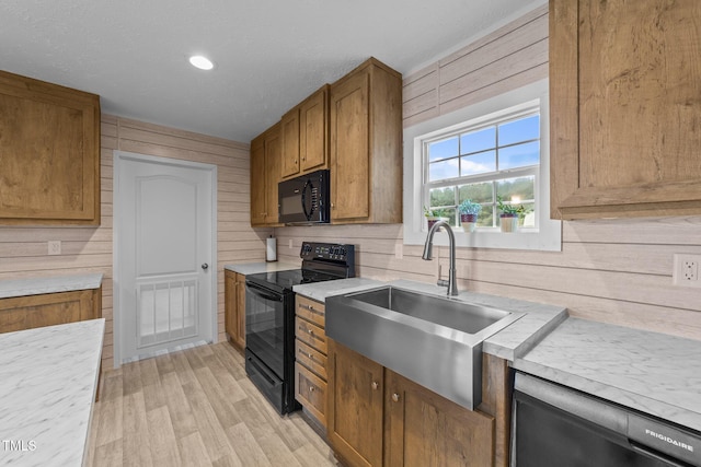 540 Pine Ridge Rd, Zebulon, NC 27597 - kitchen featuring black appliances, a sink, light countertops, wood walls, and brown cabinetry