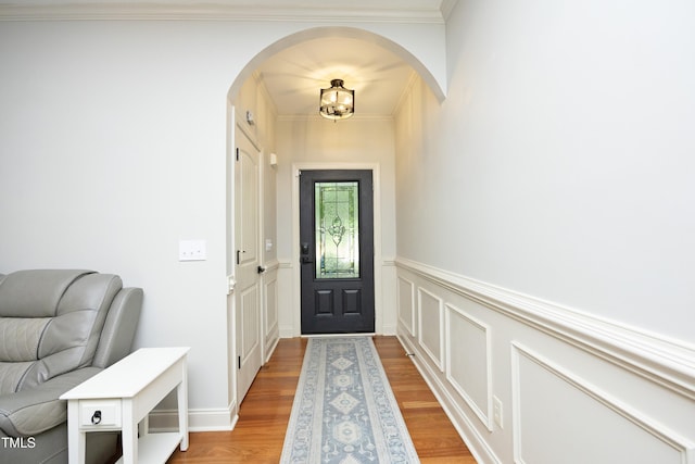 150 Churchill Rd, Louisburg, NC 27549 - entryway featuring arched walkways, light wood-style flooring, wainscoting, crown molding, and a decorative wall
