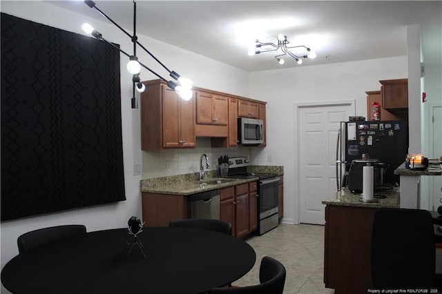 625 Marshtree Ln Unit 101, Fayetteville, NC 28314 - kitchen with stainless steel appliances, a sink, light stone counters, brown cabinets, and decorative backsplash