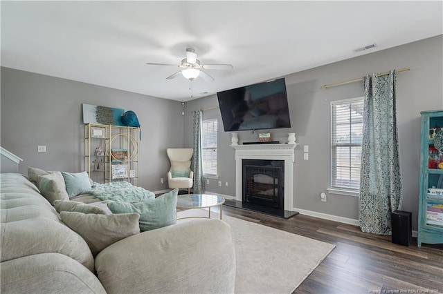 4943 Lion Heart Ln, Parkton, NC 28371 - living room featuring healthy amount of natural light, ceiling fan, a fireplace with raised hearth, and dark wood-style flooring