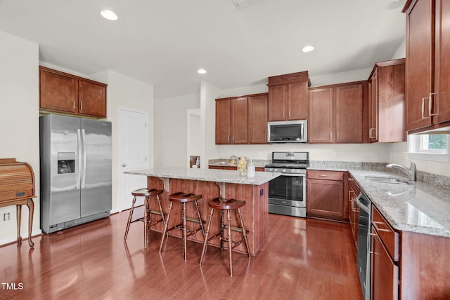 106 Elmsford St, Durham, NC 27703 - kitchen with stainless steel appliances, a sink, light stone countertops, a breakfast bar, and a center island