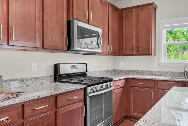 106 Elmsford St, Durham, NC 27703 - kitchen featuring stainless steel appliances, light stone countertops, a sink, and brown cabinetry