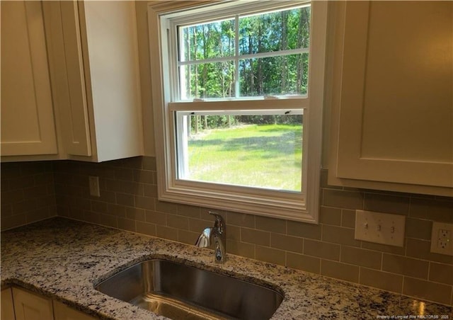 2312 Smith Rd, Hope Mills, NC 28348 - kitchen with a sink, white cabinets, tasteful backsplash, and light stone counters