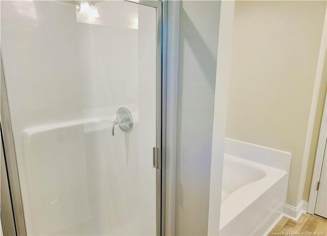 2312 Smith Rd, Hope Mills, NC 28348 - bathroom featuring a shower stall, a bath, wood finished floors, and baseboards
