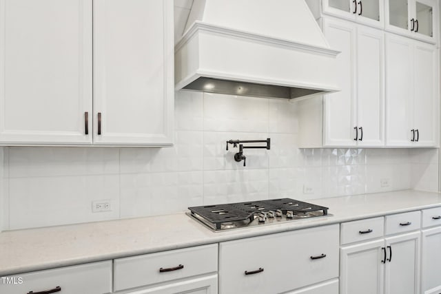 421 Gilpin Way, Cary, NC 27519 - kitchen with custom range hood, stainless steel gas cooktop, white cabinetry, backsplash, and glass insert cabinets