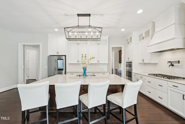 421 Gilpin Way, Cary, NC 27519 - kitchen featuring appliances with stainless steel finishes, custom range hood, backsplash, a kitchen island with sink, and glass insert cabinets