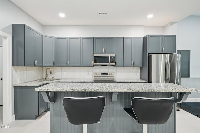 421 Gilpin Way, Cary, NC 27519 - kitchen with appliances with stainless steel finishes, a sink, a kitchen breakfast bar, light stone countertops, and decorative backsplash