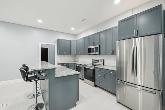 421 Gilpin Way, Cary, NC 27519 - kitchen featuring stainless steel appliances, light stone countertops, a sink, backsplash, and a kitchen breakfast bar