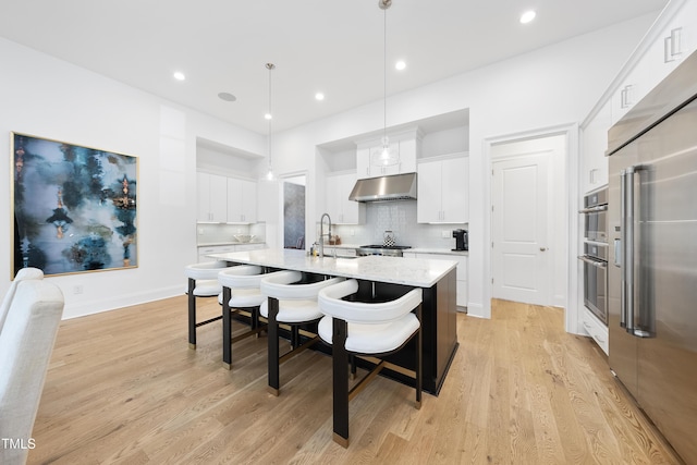 7545 Hasentree Club Dr, Wake Forest, NC 27587 - kitchen featuring appliances with stainless steel finishes, under cabinet range hood, an island with sink, backsplash, and a breakfast bar
