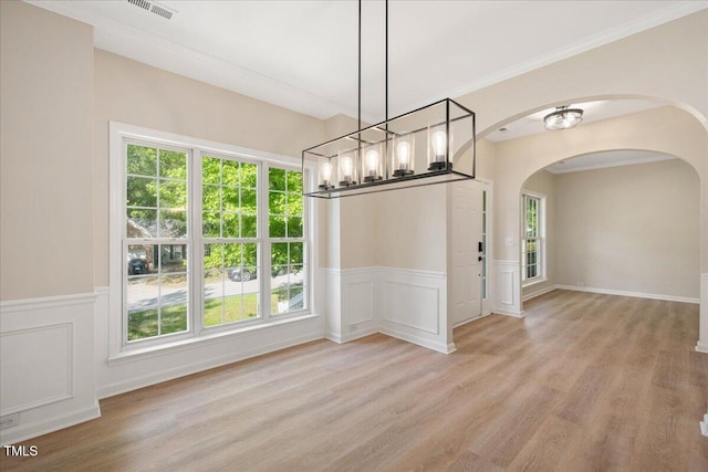 121 River Hills Dr, Clayton, NC 27527 - unfurnished dining area featuring arched walkways, wood finished floors, a chandelier, healthy amount of natural light, and a decorative wall