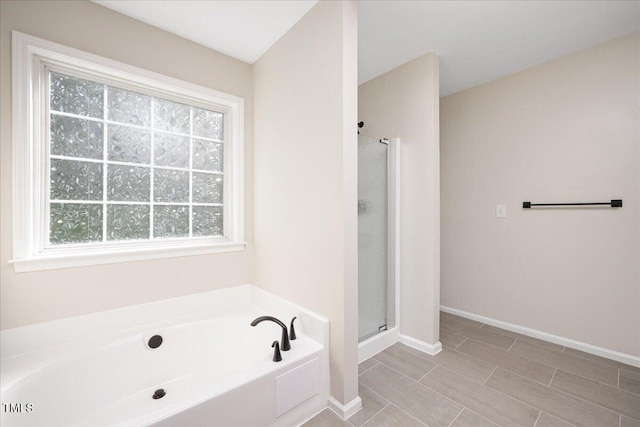 121 River Hills Dr, Clayton, NC 27527 - bathroom featuring healthy amount of natural light, a garden tub, a stall shower, and baseboards