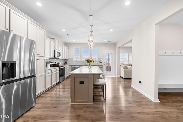 66 Arlie Ln, Lillington, NC 27546 - kitchen with stainless steel appliances, a kitchen island, dark wood-style flooring, a breakfast bar, and backsplash
