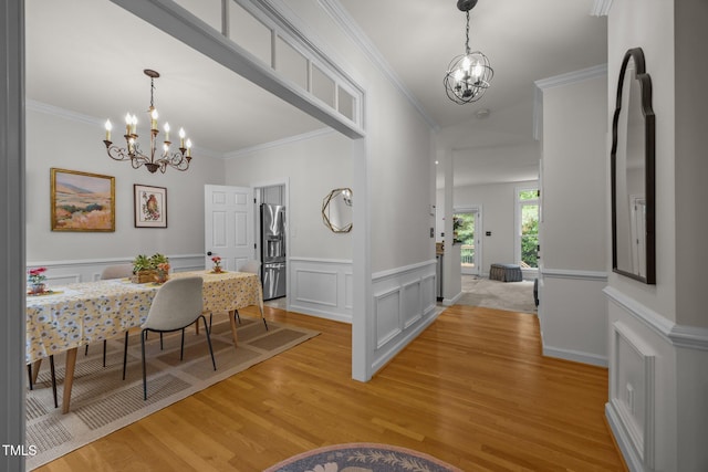 106 Fawley Ct, Cary, NC 27519 - dining area with a chandelier, light wood-type flooring, ornamental molding, wainscoting, and a decorative wall