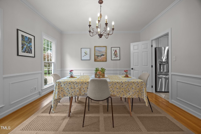 106 Fawley Ct, Cary, NC 27519 - dining room featuring light wood-type flooring, crown molding, a chandelier, a wainscoted wall, and a decorative wall