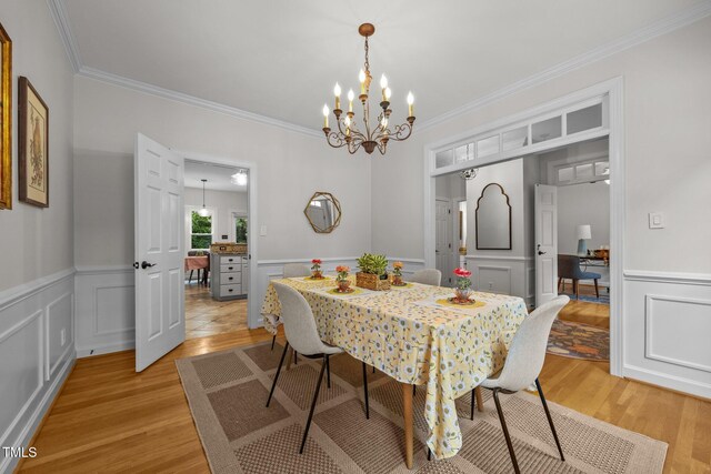 106 Fawley Ct, Cary, NC 27519 - dining room with light wood finished floors, crown molding, a chandelier, a wainscoted wall, and a decorative wall