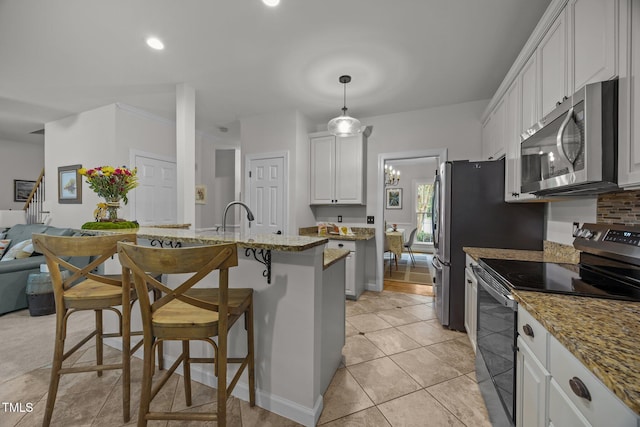 106 Fawley Ct, Cary, NC 27519 - kitchen featuring appliances with stainless steel finishes, a breakfast bar area, white cabinetry, a kitchen island with sink, and light tile patterned floors