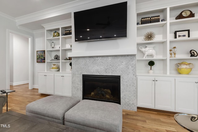 911 Canterbury Rd, Raleigh, NC 27607 - living room featuring ornamental molding, light wood finished floors, built in shelves, a tiled fireplace, and baseboards