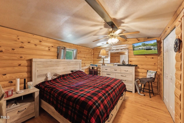 8089 Crawford Currin Rd, Oxford, NC 27565 - bedroom featuring log walls, light wood-style floors, vaulted ceiling, a textured ceiling, and a ceiling fan