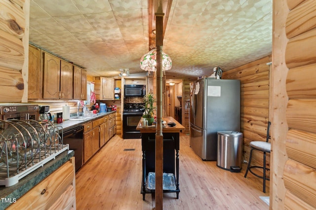 8089 Crawford Currin Rd, Oxford, NC 27565 - kitchen featuring black appliances, light wood-style floors, brown cabinets, rustic walls, and a sink